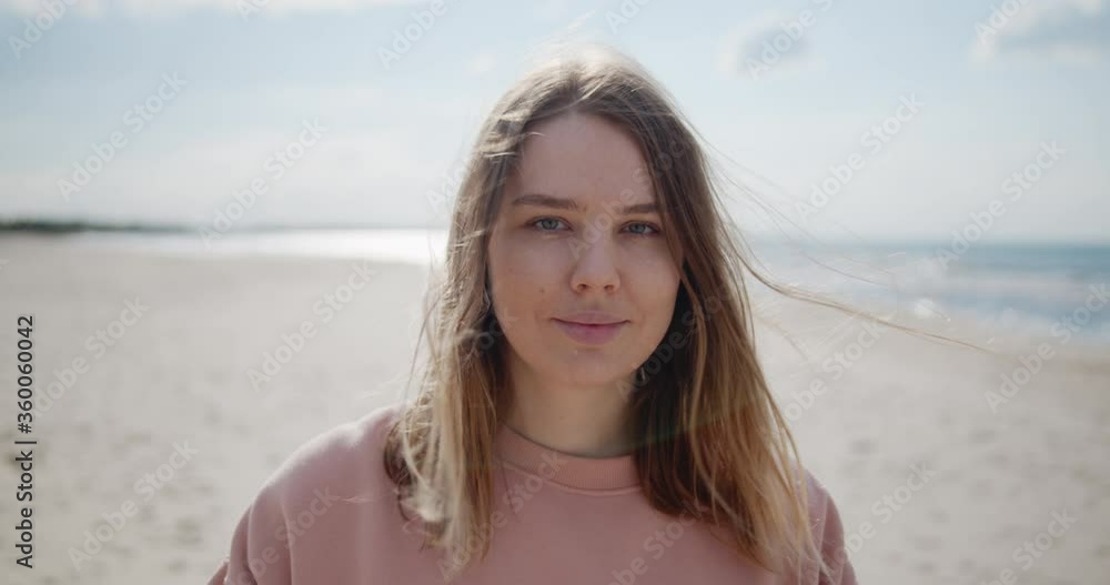 Close up portrait of a young woman standing on a beach looking at camera smiling Close up portrait of a young woman standing on a beach looking at camera smiling