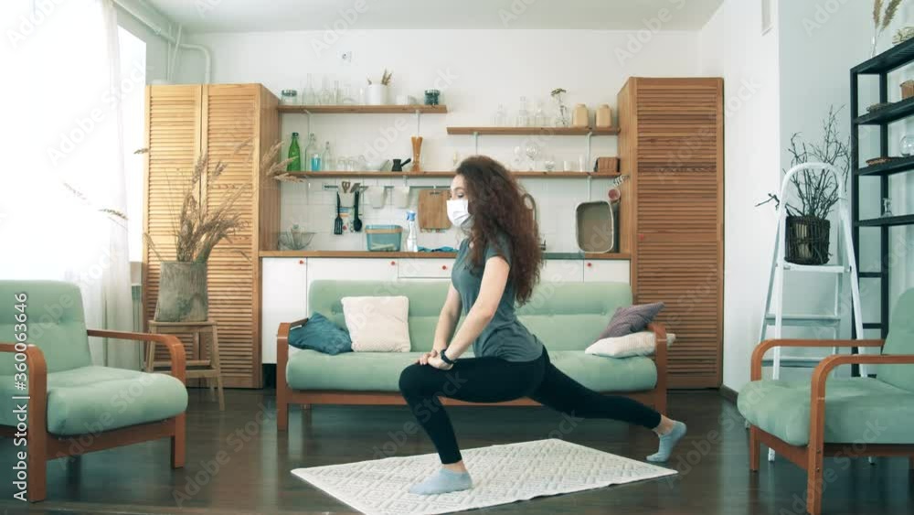 A girl in medical mask stretches at home. A girl in medical mask stretches at home.