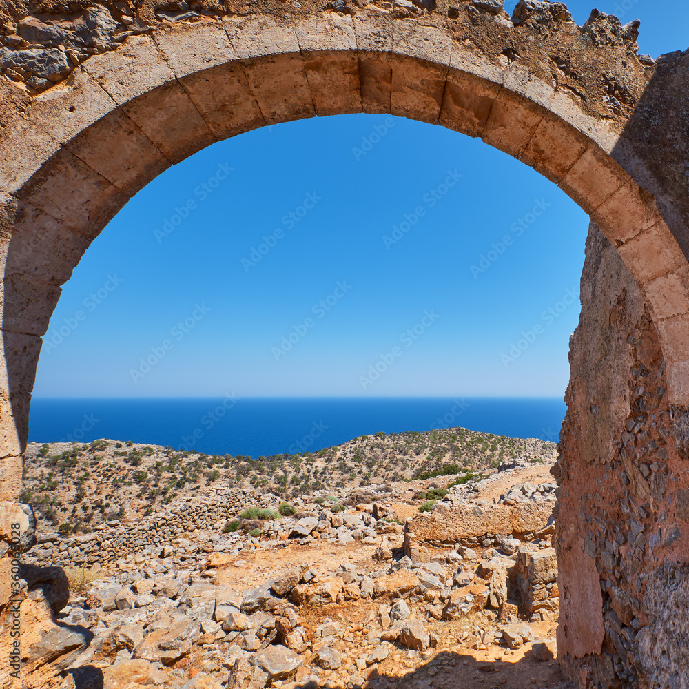 An roman Arch facing a cliff of the mediterranean sea with greenery on it
