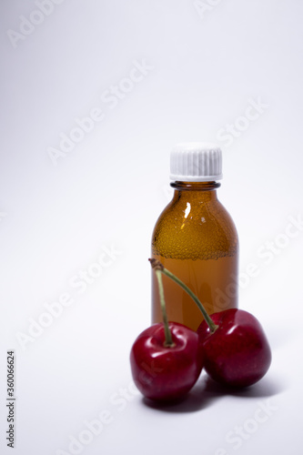 little liquid bottle with no label near cherry. body care and beauty concept. Copy space. High quality photo