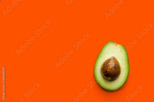 cut the avocado in half with the core on a uniform orange background