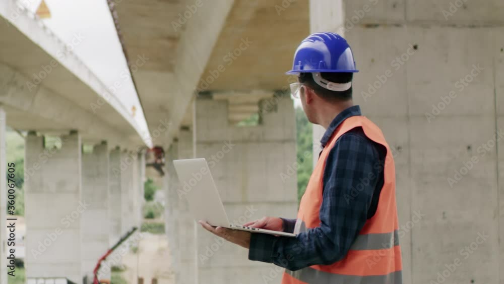 Construction engineer or an architect with a halmet and protective equipment on a building construction site using a laptop. Construction engineer or an architect with a halmet and protective equipment on a building construction site using a laptop.