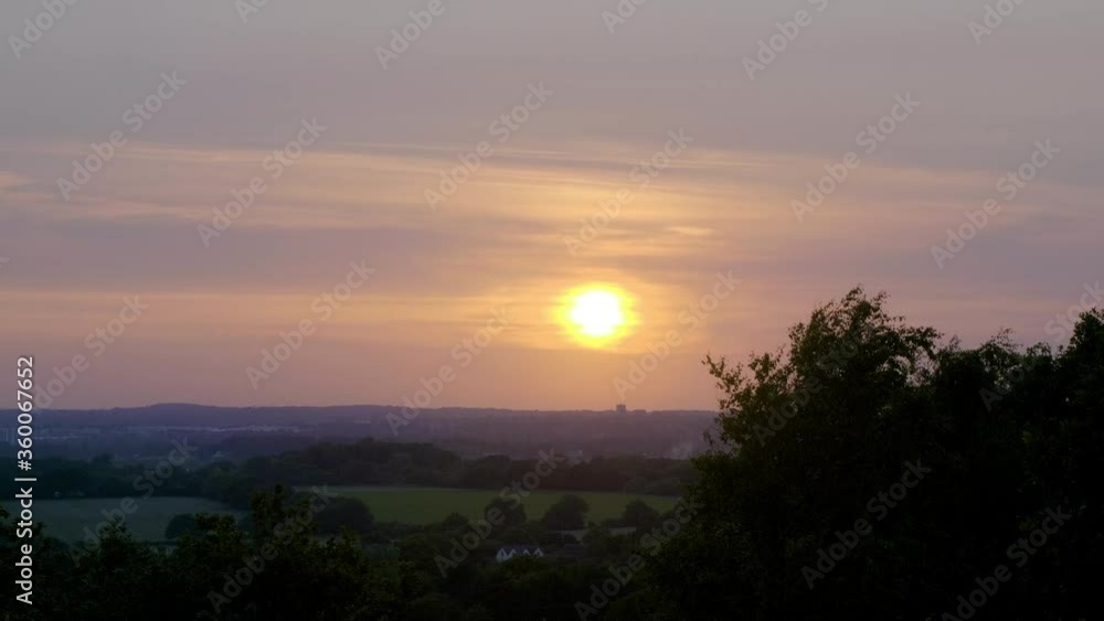 orange sun burning through hazy clouds in the evening above a large city (Birmingham, UK) orange sun burning through hazy clouds in the evening above a large city (Birmingham, UK)