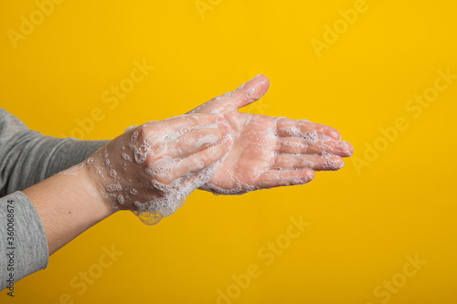 washable hands close-up on a yellow studio background. Proper hand washing as a prevention of viruses .