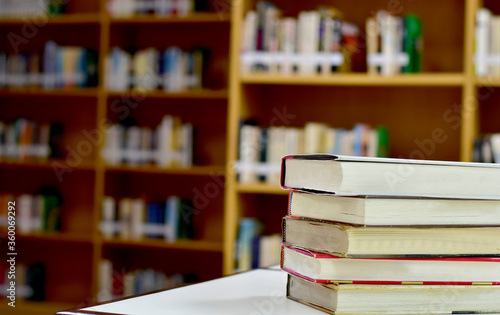 Stack of books and blurred bookshelf in the library, education background, back to school concept.
