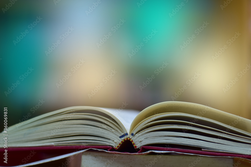 Fototapeta premium Open Book on wood table and blurred bookshelf in the library, education background, back to school concept.