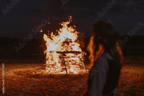 Woman watching midsummer holidays night fire in Latvia