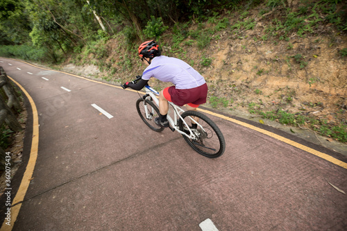 Woman riding bike down a slope with fast speed on mountain trail