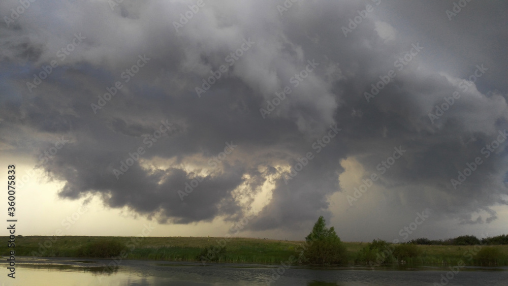 thunderstorm over the river. low clouds before the rain. a thunderstorm and a hurricane are approaching the pond. tornado. the sky is in clouds. bad weather. thunderstorm over the river. low clouds before the rain. a thunderstorm and a hurricane are approaching the pond. tornado. the sky is in clouds. bad weather.