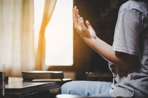 Teenage girl hand with Bible praying in the morning.