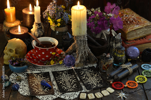  Still life with tarot cards layout, burning candles and runes on witch table. Esoteric, wicca and occult background with magic objects, fortune telling and divination ritual