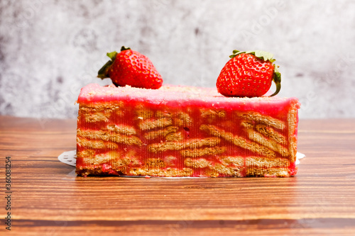 A picture of  batik  with strawberry on top. It is frozen cake made with  egg  butter  biscuits  milk  chocolate powder and strawberry flavour.         