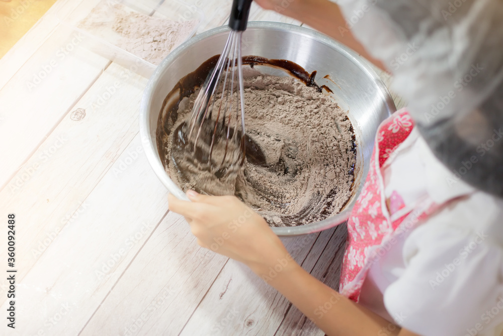 Fototapeta premium A girl making chocolate brownies. Preparation for maxing chocolate cake or homemade brownie cake.