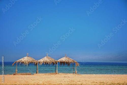 Three sunshades  made from palm leaves on the beach of the Red Sea