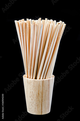 Wheat straw for drinking water in wooden glass on black background. photo