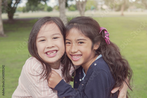 Happy and healthy mixed race multiethnic young girls hugging and smiling in the park, best friend kids and children friendship, all lives matter, no to racism, diversity concept