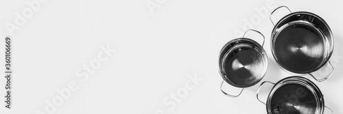 Three empty metal pots without a lid on a light background. Top view, flat lay. Banner