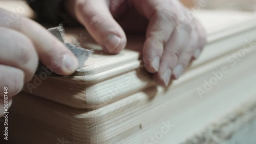 Close-up of a man's hands sanding beveled edges as he puts the final touches on a woodworking project.