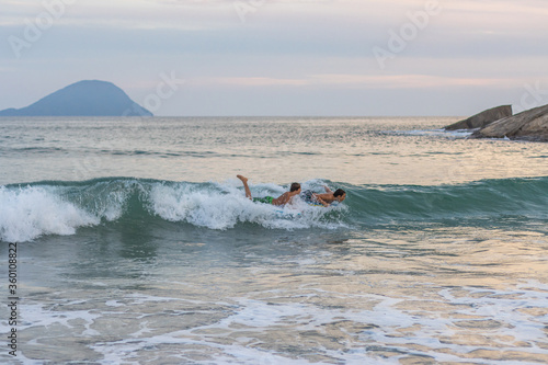 Garotos fazendo manobras radicais com suas pranchas de bodyboard na praia © Luciano Ribeiro