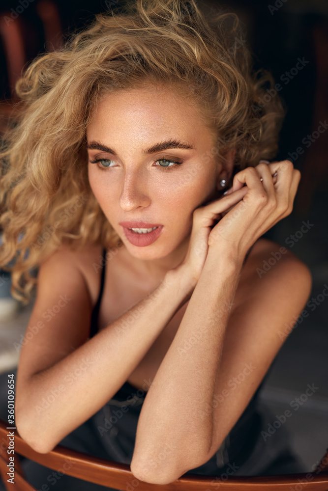 Obraz premium Beautiful Woman. Sexy Blonde Model Relaxing On Wooden Chair. Healthy Natural Look In Beauty Portrait. Female Curly Hairstyle And Nude Makeup.