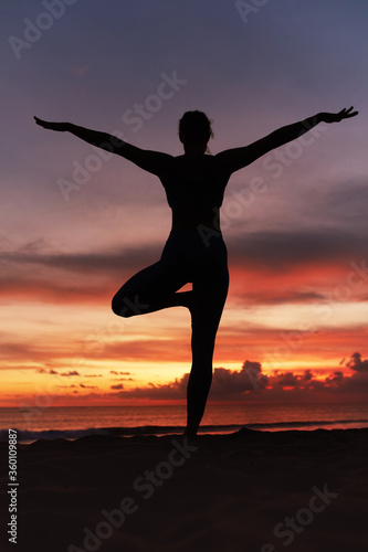 Yoga Poses. Woman Standing In Tree Pose Balancing Asana On Ocean Beach. Female Silhouette Practicing Vrikshasana At Beautiful Sunset. Yoga As Exercise For Lifestyle.