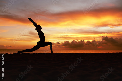 Yoga Poses. Woman Standing In Warrior Pose Asana On Ocean Beach. Female Silhouette Practicing Virabhadrasana At Beautiful Sunset. Yoga As Exercise For Lifestyle. © puhhha