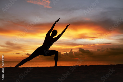 Yoga Poses. Woman Practicing Side Angle Asana On Ocean Beach. Female Silhouette Standing In Parivrtta Parsvakonasana At Beautiful Sunset. Yoga As Exercise For Lifestyle.
