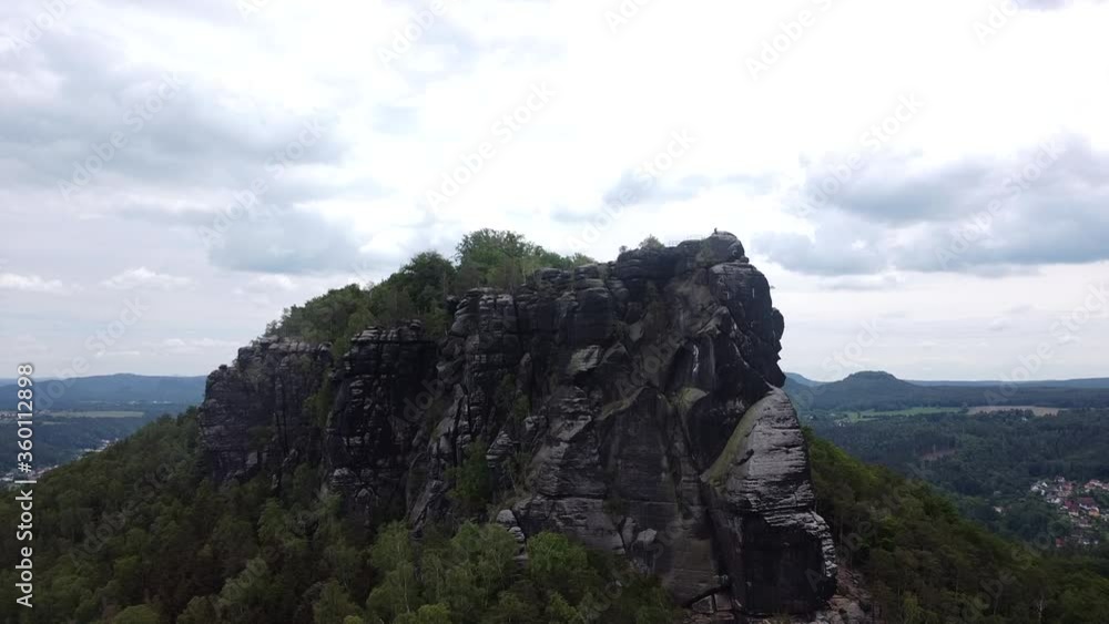 Drone rising up to iconic mountain rock formation in eastern Europe on a bright but cloudy day