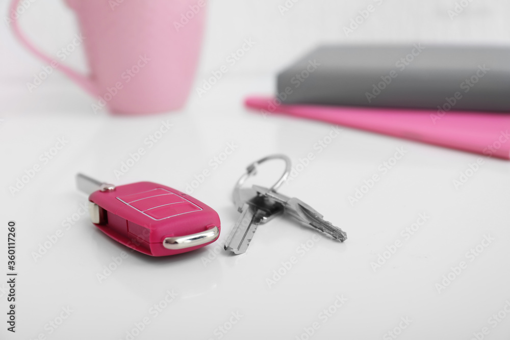 Keys from house and car on table in room Keys from house and car on table in room