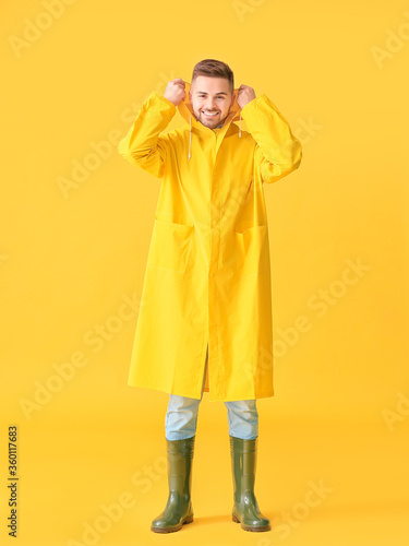 Young man in raincoat on color background photo