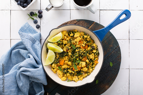 Vegan tofu scramble with spinach and carrots for breakfast with coffee on white table
