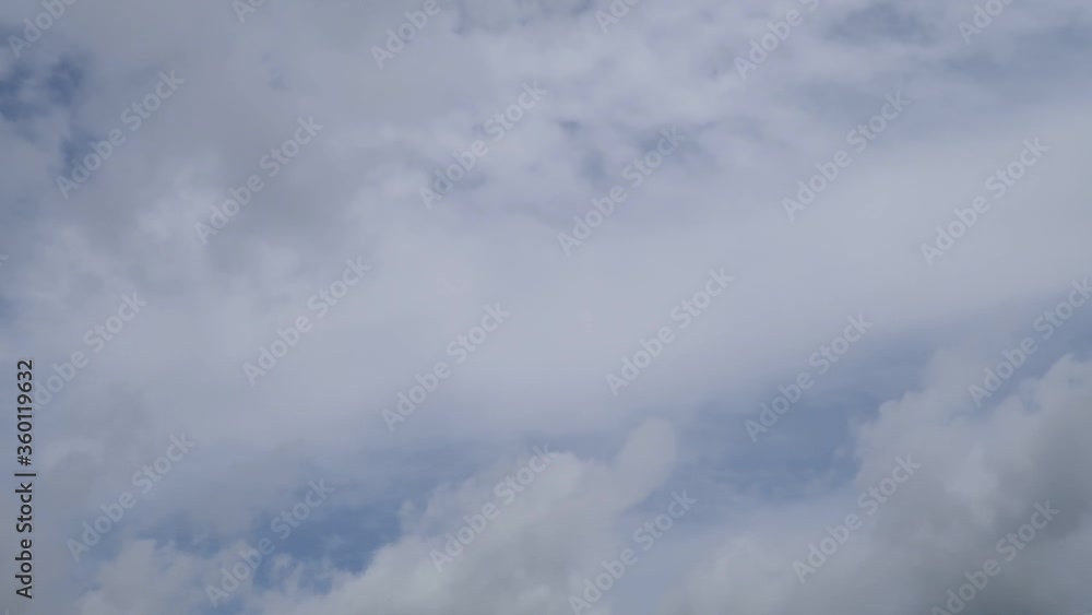 TimeLape of dramatic fast moving white cumulus & cirrocumulus clouds or puffy fluffy cloudscape on beautiful sunny blue sky background in tropical summer or spring sunlight & sun rays at sunshine day 