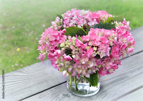romantic round bouquet of pink hydrangea in a glass vase put on a table in ga...