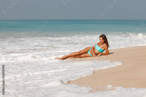 Attractive brunette girl take sunbath on the beach  happy female wearing stylish colorful swimwear  enjoying summer holidays