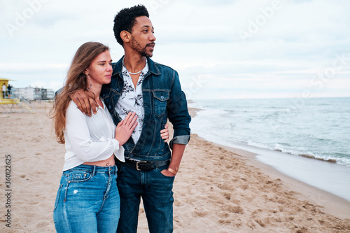 young interracial couple at the beach taking a walk