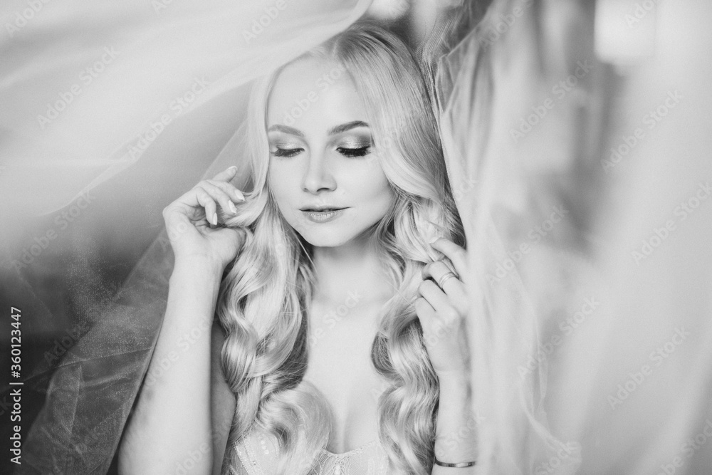 Monochrome portrait of sensuality and charming smiling young blondie. Beautiful sexy lady with long hair, and perfect make up dreaming with closed eyes. Concept of beauty. Morning of bride.