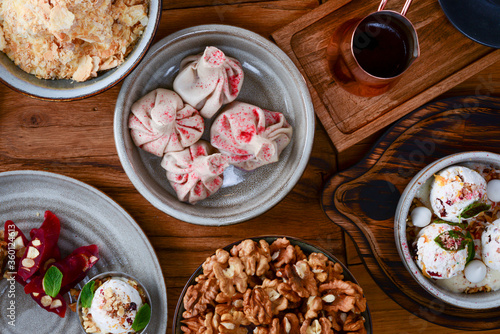 Sweet khinkali with cherry, churchhela, ice cream and nuts served on a wooden table. Traditional Georgian desserts