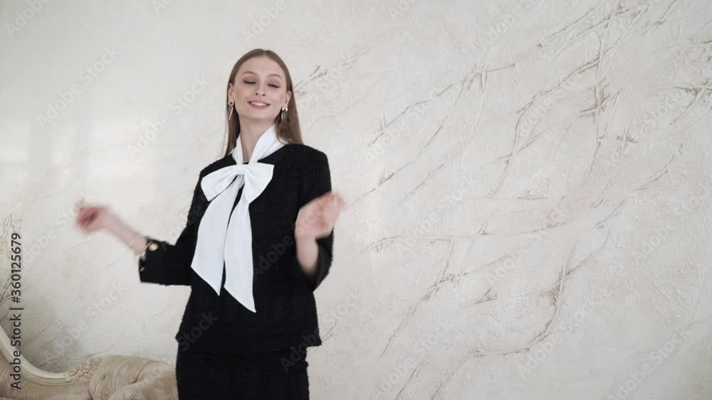 A business woman poses in a black jacket and trousers in a home interior. Sexy female model in a grey suit walks forward . 4 K A business woman poses in a black jacket and trousers in a home interior. Sexy female model in a grey suit walks forward . 4 K