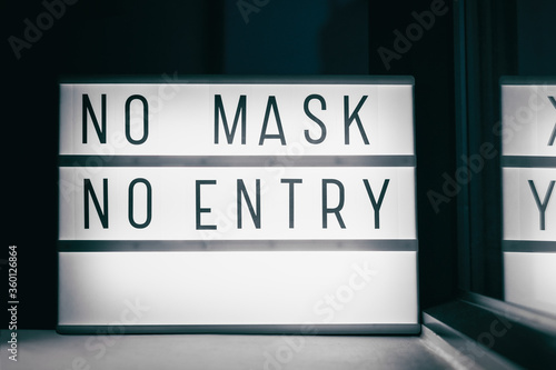 Fototapeta Naklejka Na Ścianę i Meble -  Covid-19 mask obligatory to enter stores . SIGN NO MASK NO ENTRY at storefront window. Face covering wearing mandatory when shopping outside of home. Coronavirus prevention measure.