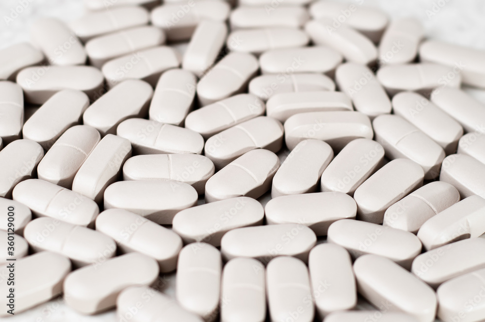 White oblong tablets in the form of capsules on a light background White oblong tablets in the form of capsules on a light background
