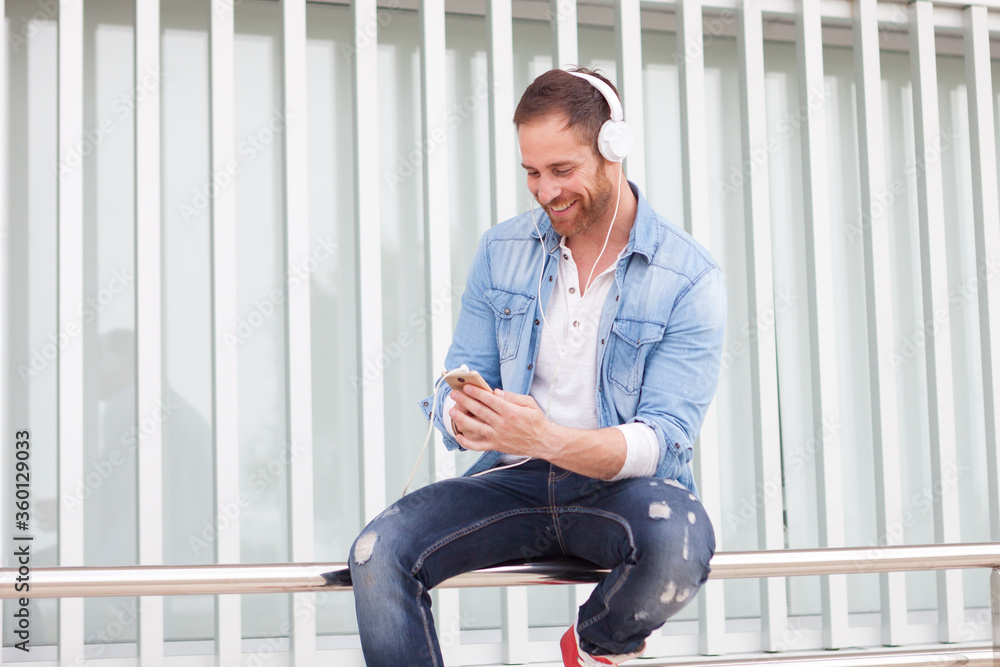 Casual man in the street listening music with his mobile