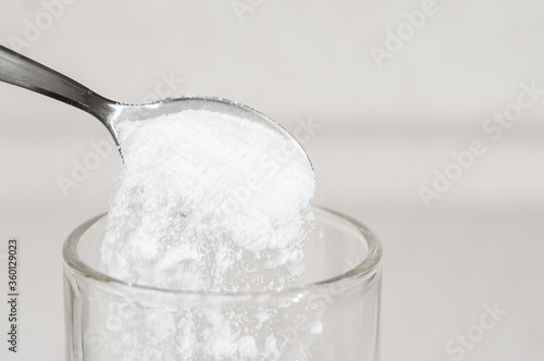 Tapeta White tasteless creatine powder on a teaspoon spills out into a transparent glass