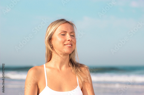 beautiful girl in white clothes on the background of the sea hands folded on her chest