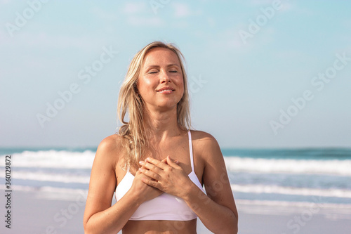 beautiful girl in white clothes on the background of the sea hands folded on her chest