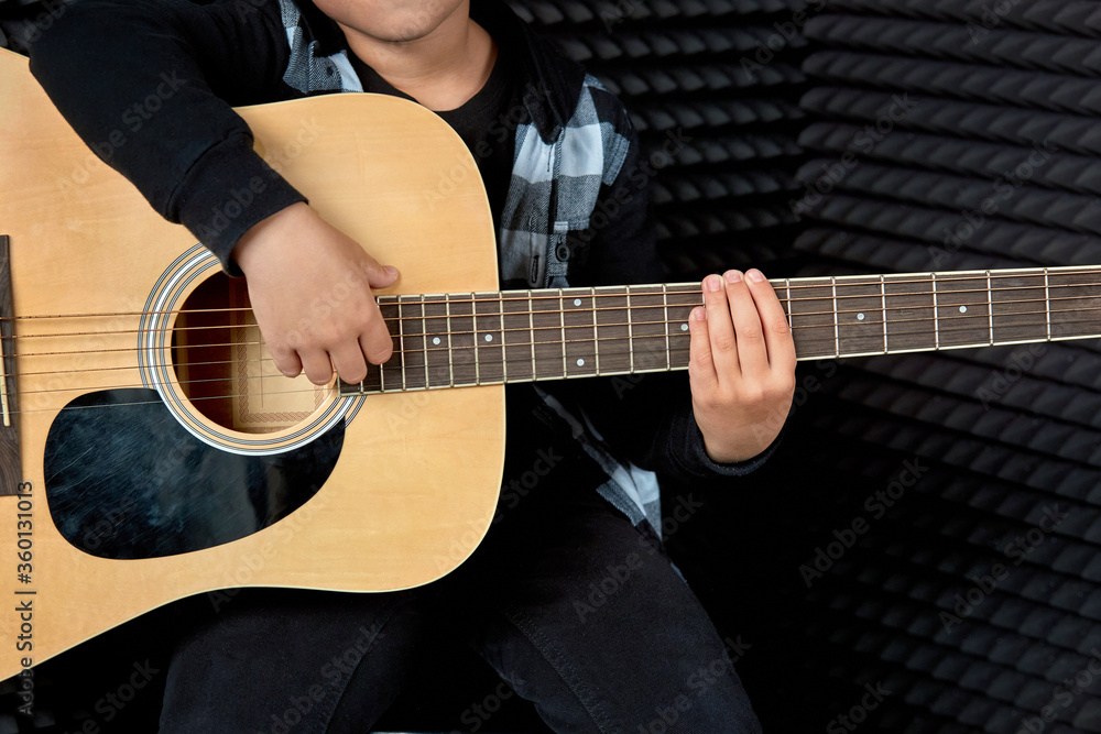 Fototapeta premium Photo without a face. Cute brunette boy plays the guitar