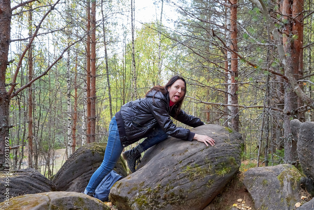 Beautiful young woman near very big stone in the forest with sprice in autumn, spring or summer