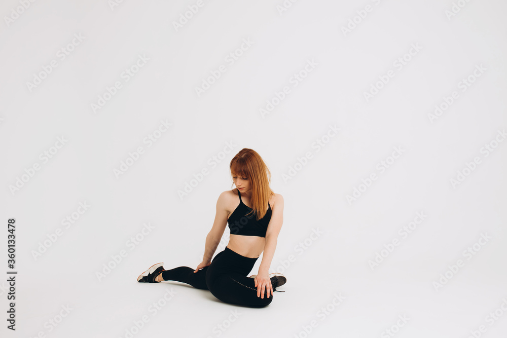 Fototapeta premium Fit girl warming up. Full length of young african girl in sportswear stretching her arms on white background. Stretching and motivation