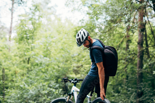 Rear view of male cyclist cycling on mountain road on a sunny day. Professional cyclist riding a bike in the forest outdoor.