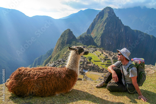Tourist and llama sitting in front of Machu Picchu, Peru photo