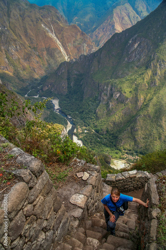 Tourist climbing old incan stairs to the top of Wayna Picchu for the views of Machu Picchu, Peru